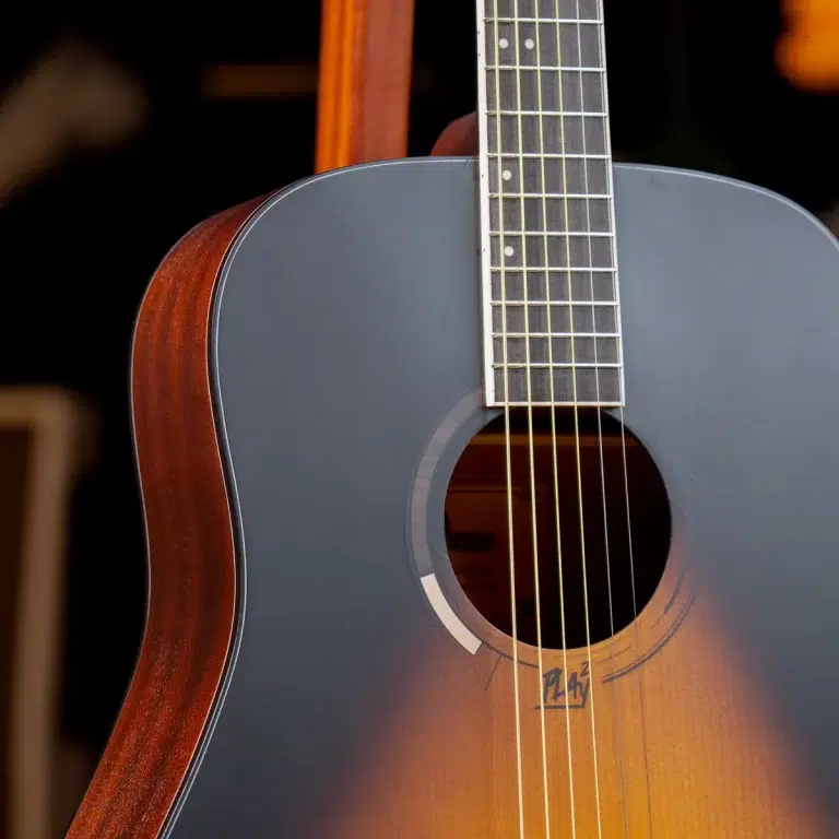 Close-up of an acoustic guitar's gray-blue top with a sunburst edge, strings running over the soundhole and fretboard nearby ขายราคาพิเศษ
