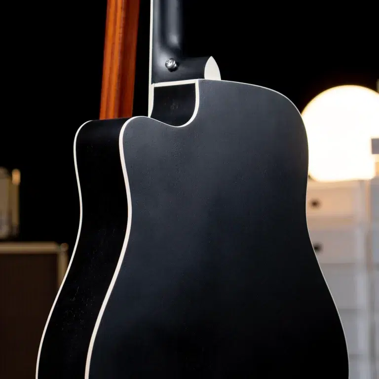 Close-up of a black electric guitar body with white binding, seen from the back against a dark background. ขายราคาพิเศษ
