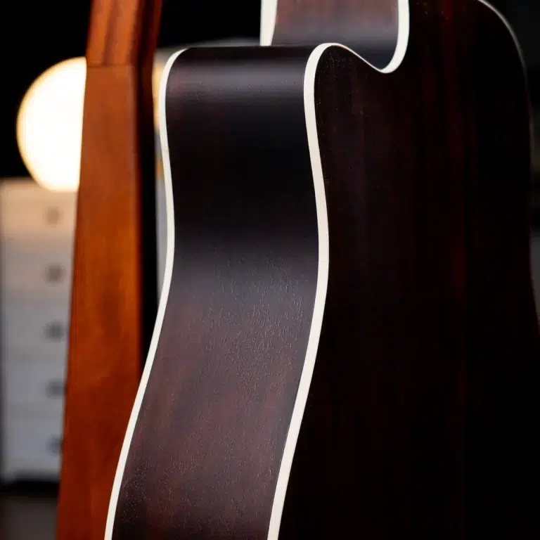 Close-up of a dark wooden guitar body with white binding, showing curved edges and glossy finish. ขายราคาพิเศษ