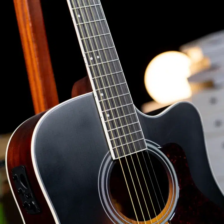 Close-up of a dark acoustic guitar neck and body, strings running along the fretboard toward the sound hole. ขายราคาพิเศษ