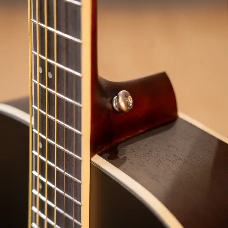 Close-up of an acoustic guitar neck and body, showing frets, strings, and a strap button near the heel area. ขายราคาพิเศษ