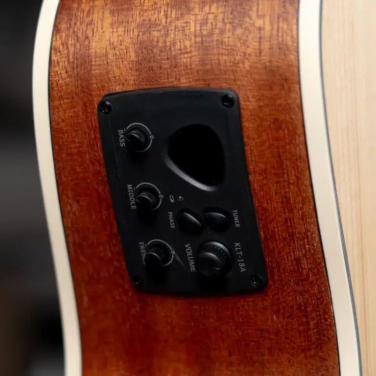 Close-up of a guitar's built-in preamp on a wooden body, showing Bass, Middle, Treble, Volume and tuner controls ขายราคาพิเศษ
