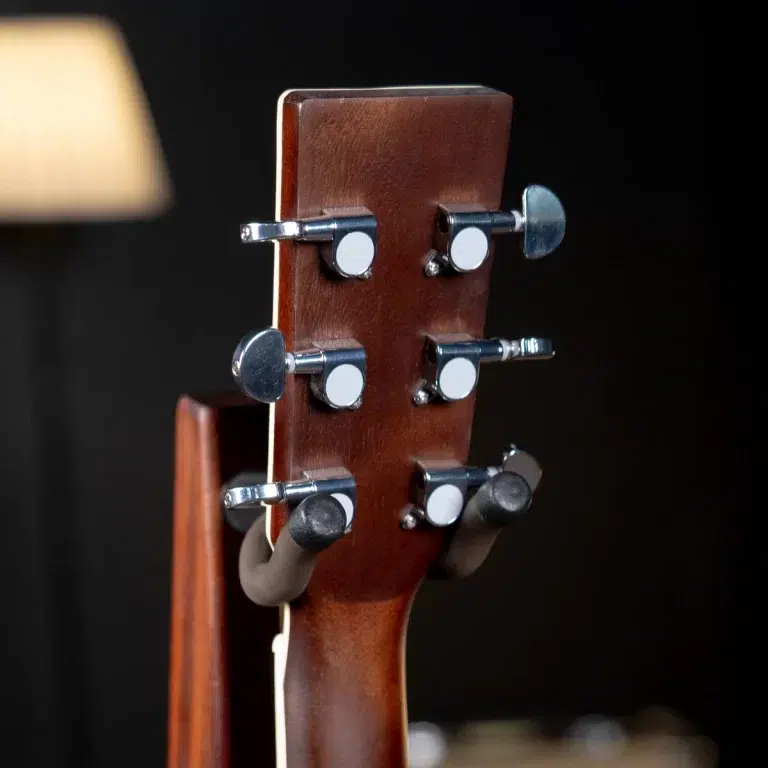 Close-up of a guitar headstock with six silver tuning pegs and a warm wood grain against a dark background. ขายราคาพิเศษ