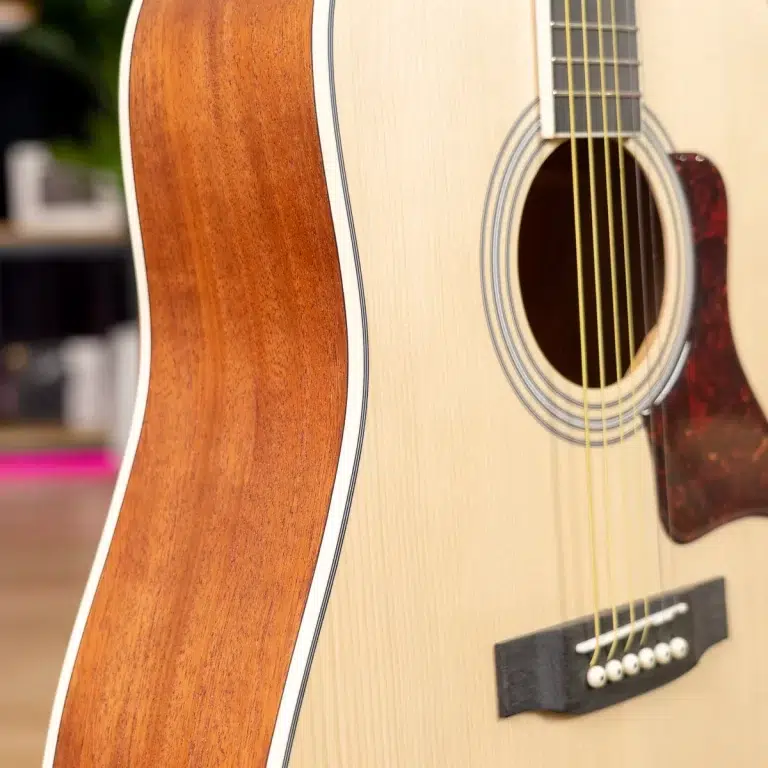 Close-up of an acoustic guitar body: light wood top, sound hole, and six strings visible near the bridge. ขายราคาพิเศษ
