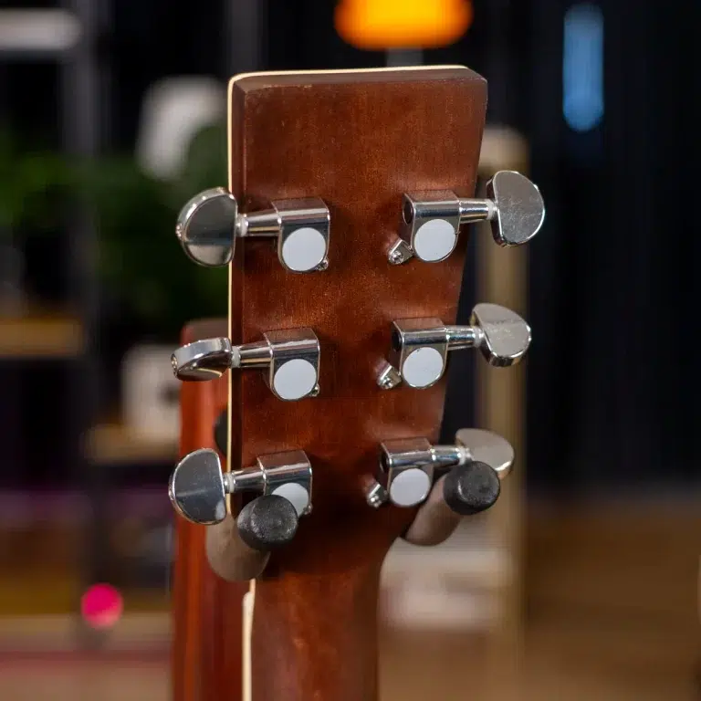 Close-up of a guitar headstock with chrome tuning pegs on a brown wooden neck ขายราคาพิเศษ