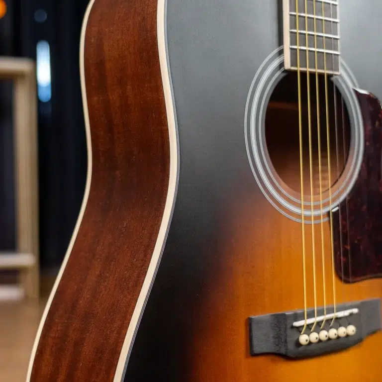 Close-up of an acoustic guitar body with a sunburst finish, showing the soundhole and strings over the bridge. ขายราคาพิเศษ