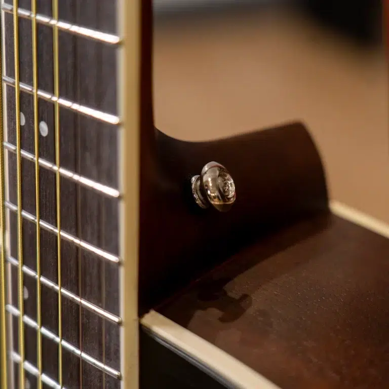 Close-up of a guitar neck with frets and strings on the left, and the dark wooden body with a chrome control knob in the foreground. ขายราคาพิเศษ