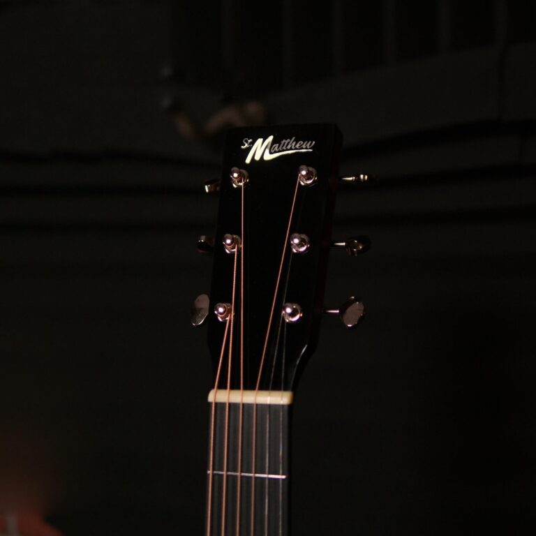 Close-up of a black guitar headstock with six tuning pegs and strings; brand name 'St Matthew' visible. ขายราคาพิเศษ
