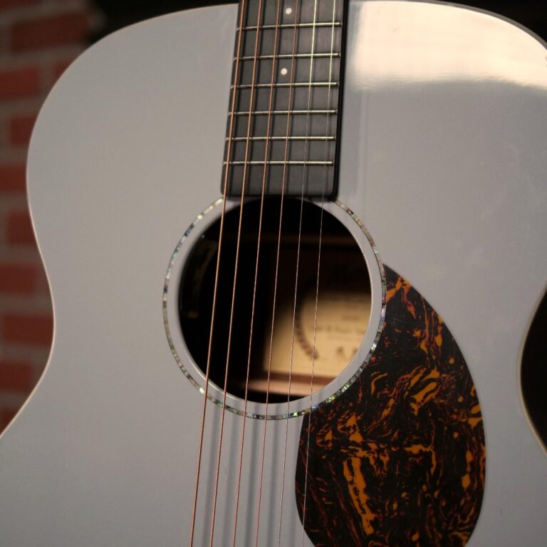 Light gray acoustic guitar close-up showing soundhole, six strings, and a tortoiseshell pickguard in the foreground. Note: concise and informative for screen readers, focusing on the image's meaning. ขายราคาพิเศษ