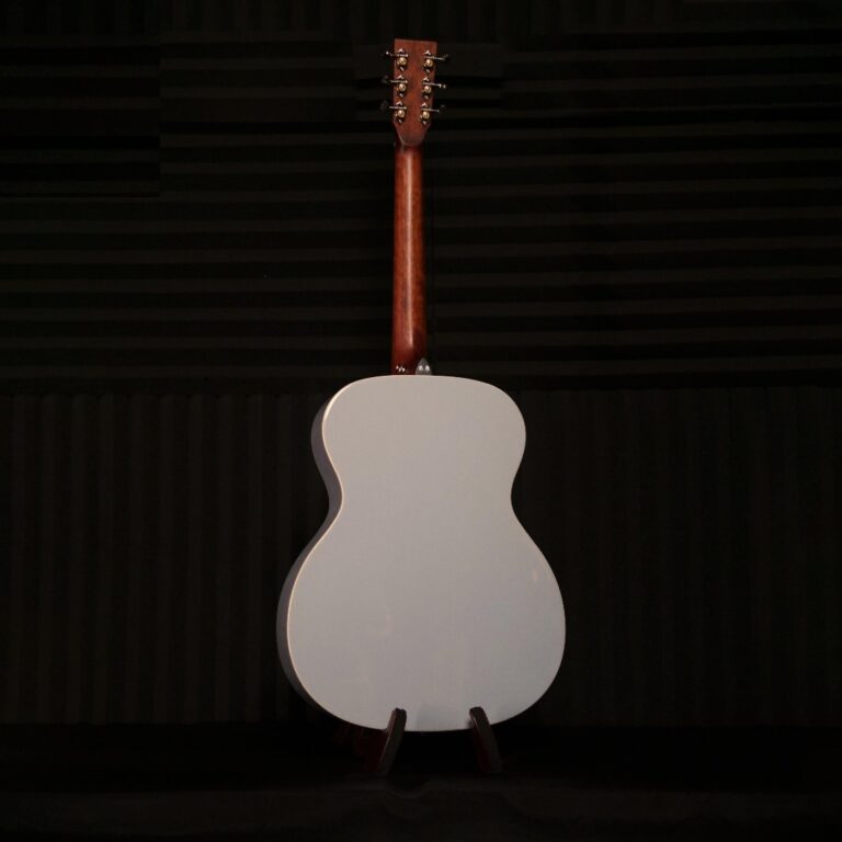 Back view of a white acoustic guitar on a stand in a dark recording studio. ขายราคาพิเศษ