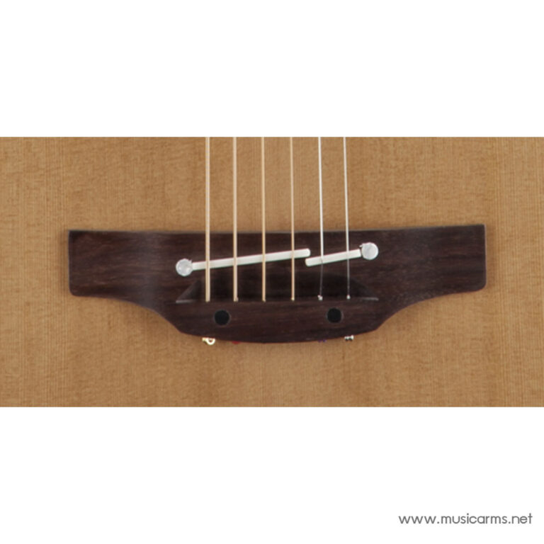 Close-up of an acoustic guitar bridge showing the saddle and six strings anchored to the body on a light-brown top. ขายราคาพิเศษ