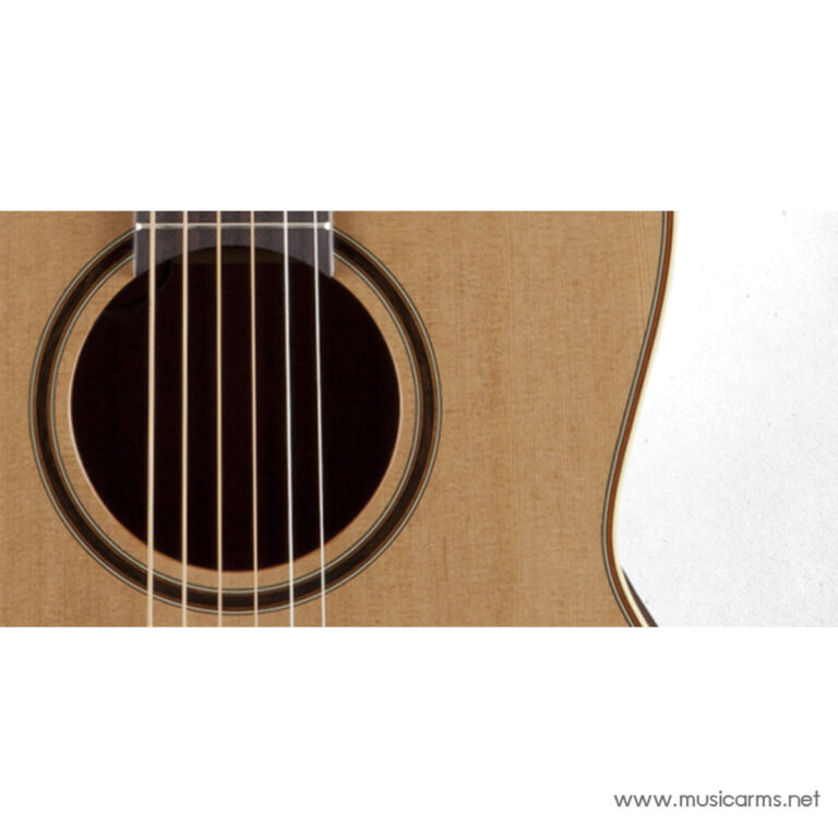 Close-up of an acoustic guitar soundhole with six strings and wooden body edges visible on a light background ขายราคาพิเศษ