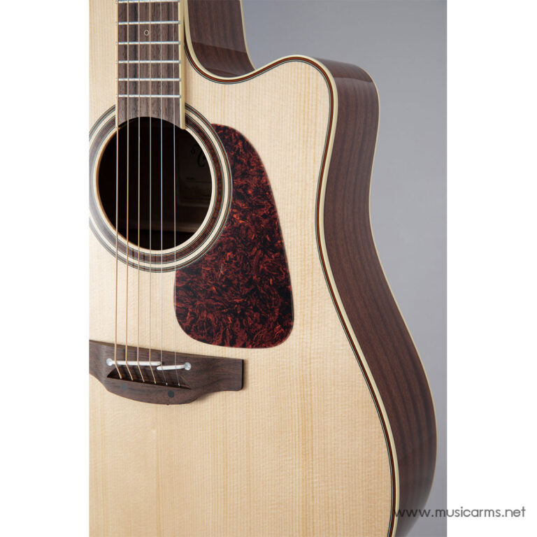 Close-up of an acoustic guitar's soundhole, light top wood, dark pickguard, and brown back/sides with strings running along the fretboard edge. ขายราคาพิเศษ