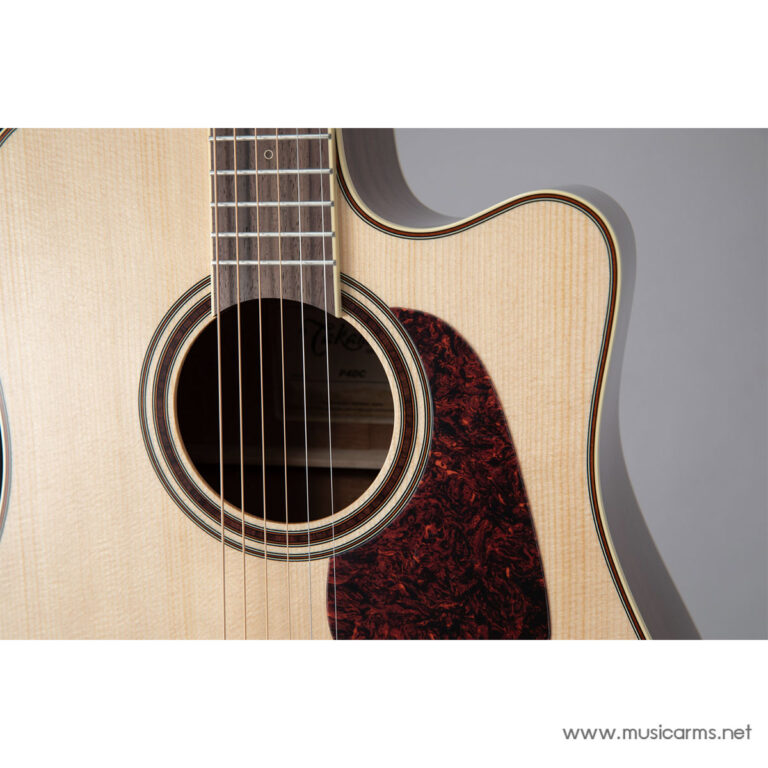 Close-up of an acoustic guitar showing the soundhole, strings, and tortoiseshell pickguard on a light wood body. ขายราคาพิเศษ