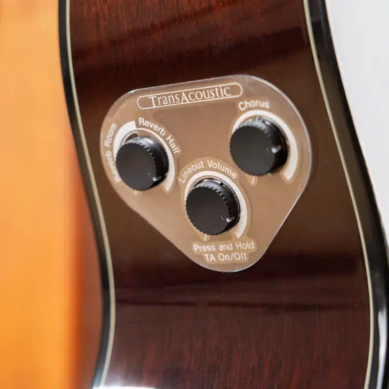 Close-up of a guitar body control panel labeled TransAcoustic with knobs for Reverb, Chorus, and Lineout Volume. ขายราคาพิเศษ