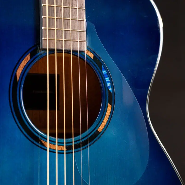 Close-up of a blue acoustic guitar showing the sound hole, strings, and part of the body. ขายราคาพิเศษ