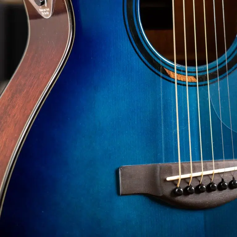 Close-up of a blue acoustic guitar showing the body, strings, and bridge. ขายราคาพิเศษ