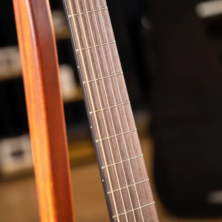 Close-up of a wooden guitar neck with frets and strings visible ขายราคาพิเศษ