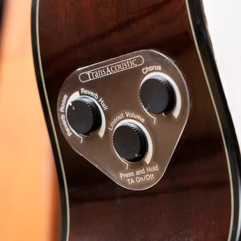 Close-up of a guitar's TransAcoustic control plate with knobs for Reverb Hall, Chorus, and Lineout Volume along with 'Press and Hold TA On/Off' text. ขายราคาพิเศษ