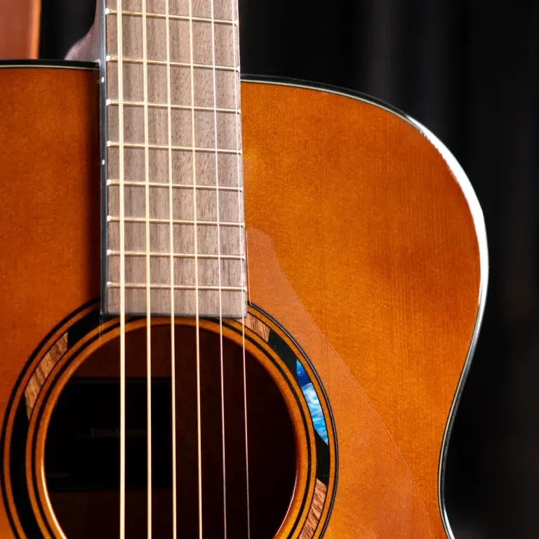 Close-up of an acoustic guitar showing the fretboard with strings, the soundhole, and the sunburst wooden body edge. ขายราคาพิเศษ