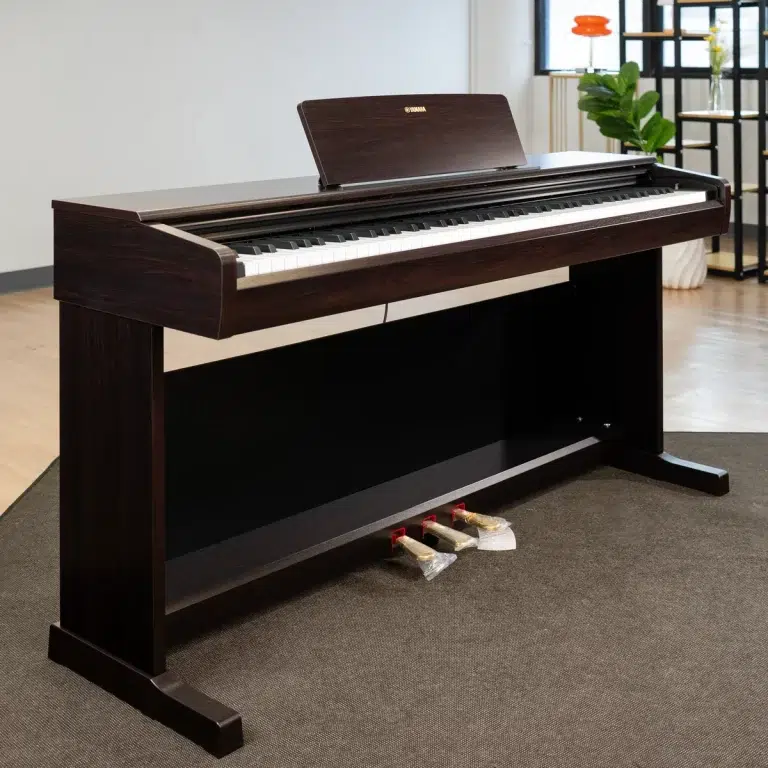 Dark wood Yamaha digital piano in a showroom, with three pedals wrapped in plastic beneath the keyboard. ขายราคาพิเศษ