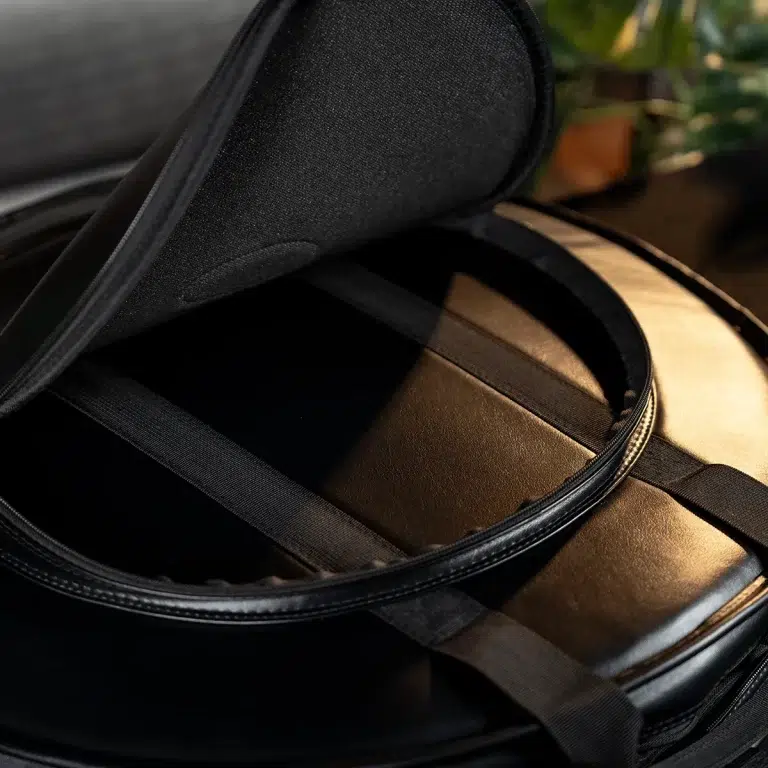 Open round black instrument case with padded brown lining and securing straps inside, ready to hold a banjo or similar instrument. ขายราคาพิเศษ