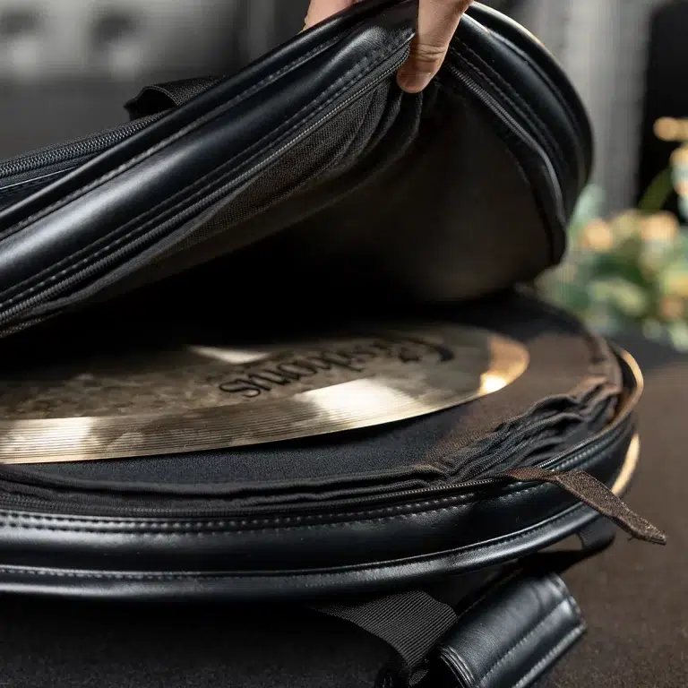 Close-up of a hand opening a black bag to reveal a shiny circular cymbal or metal disc inside ขายราคาพิเศษ