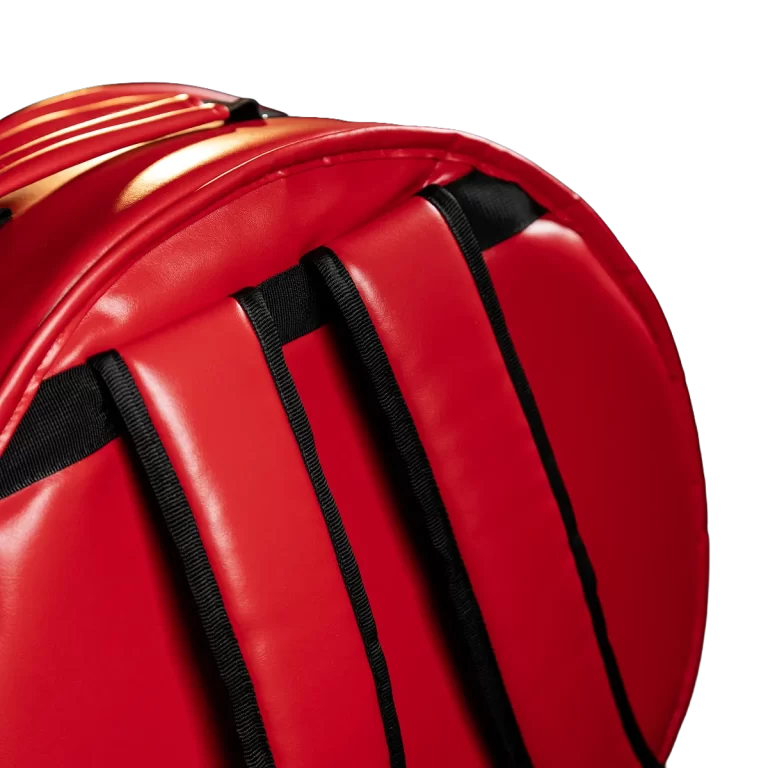 Close-up of a red padded backpack shoulder strap with black webbing on a dark background, highlighting padding and stitching for comfort. ขายราคาพิเศษ
