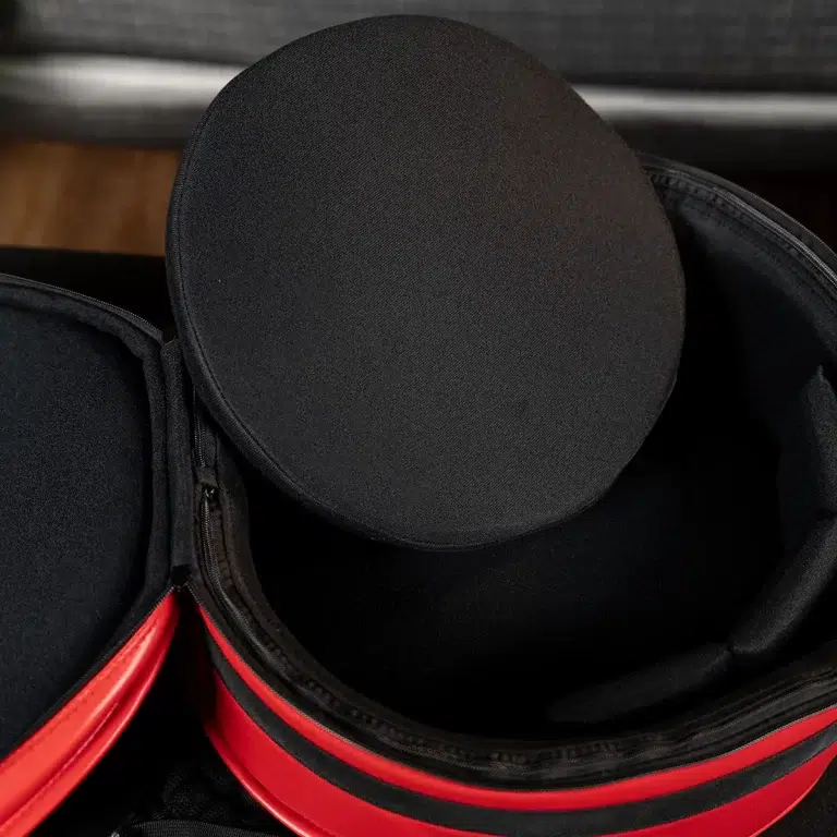 Black round hat-like object inside an open bag with red lining and visible zippers. ขายราคาพิเศษ