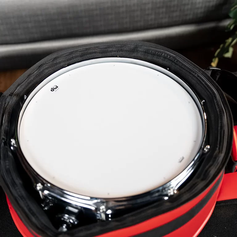 Close-up of a white drumhead inside a black and red carrying case, ready for transport. ขายราคาพิเศษ