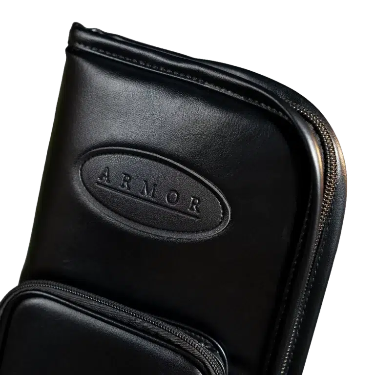 Close-up of a black leather bag with an oval embossed ARMOR logo and a visible zipper edge. ขายราคาพิเศษ