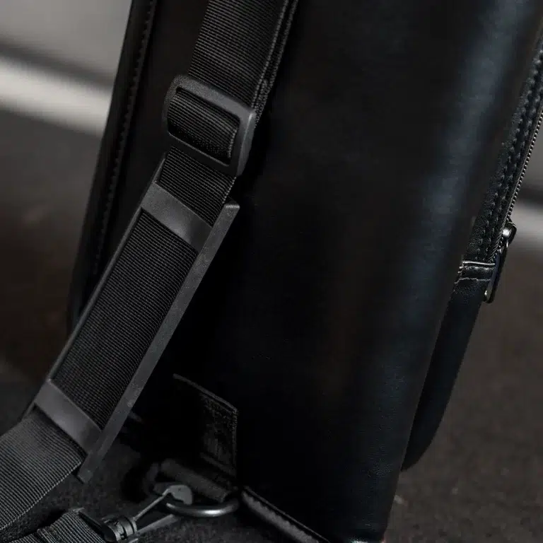 Close-up of a black bag with an adjustable strap and plastic buckle. ขายราคาพิเศษ