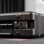 Close-up of a black textured hard case with a partially open latch and hinge details. ขายราคาพิเศษ
