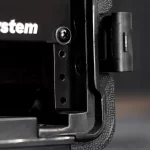 Close-up of a black metal bracket on a device, showing a screw, three holes in a vertical rail, and a textured edge at right, on a dark background. ขายราคาพิเศษ