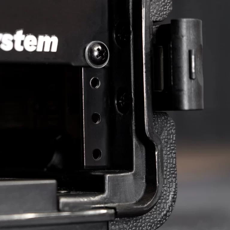 Close-up of a black metal bracket on a device, showing a screw, three holes in a vertical rail, and a textured edge at right, on a dark background. ขายราคาพิเศษ