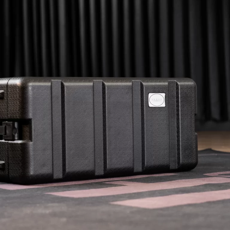Black rugged protective case on a stage floor with a small white circular label reading 'ARMOR'. ขายราคาพิเศษ