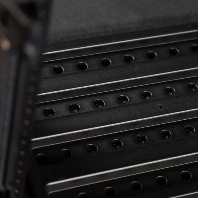 Close-up of a black metal server rack with perforated mounting rails and evenly spaced holes, conveying a data center component. ขายราคาพิเศษ