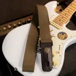 White electric guitar with a brown woven strap draped over it, leather strap end reads 'LOCK-IT' ขายราคาพิเศษ