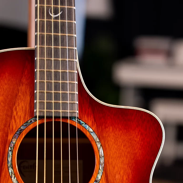 Acoustic guitar close-up showing the wooden body, neck and six strings with a decorative iridescent rosette around the soundhole. ขายราคาพิเศษ