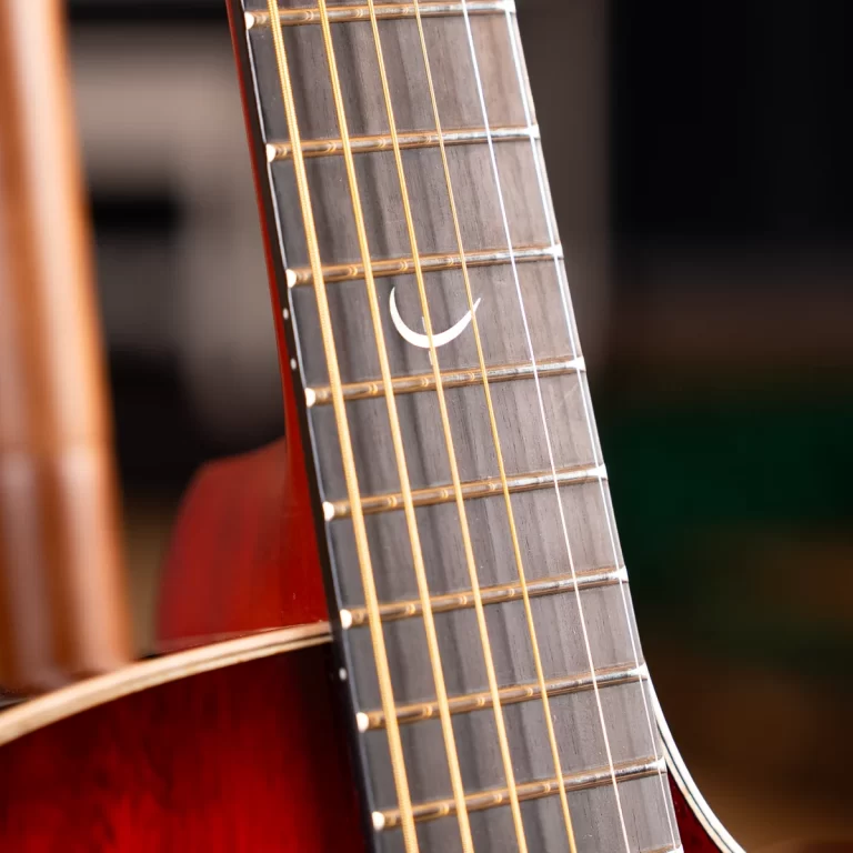 Close-up of a guitar fretboard with six strings and a white crescent inlay on the wood surface] , ขายราคาพิเศษ