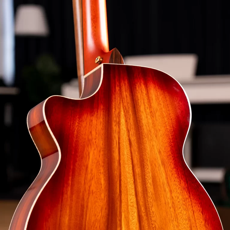 Close-up of the back of a glossy sunburst acoustic guitar, highlighting the wood grain and curved body against a dark background. ขายราคาพิเศษ
