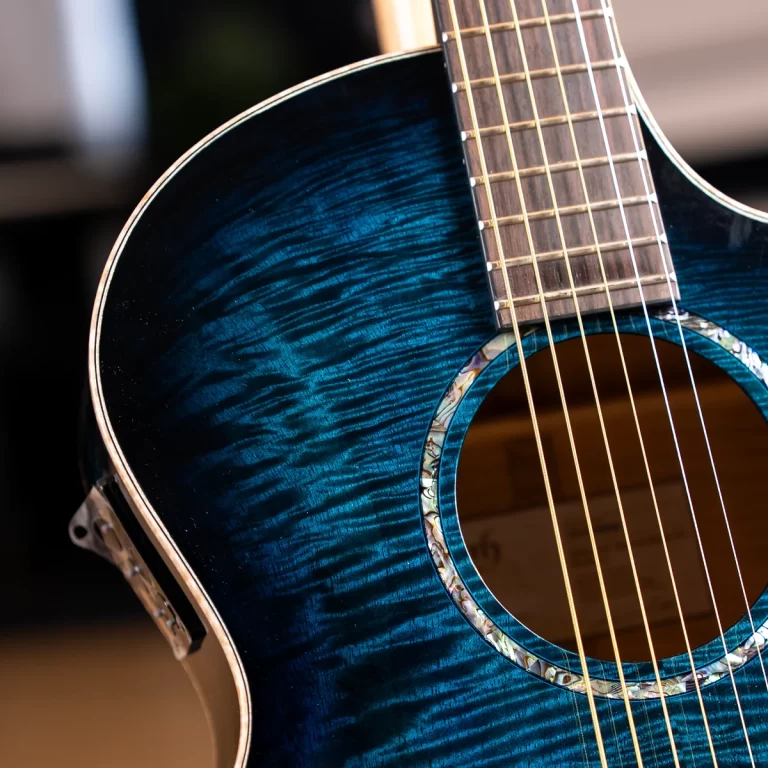 Close-up of a blue acoustic guitar body showing the grainy finish, soundhole, and part of the neck with strings visible. ขายราคาพิเศษ
