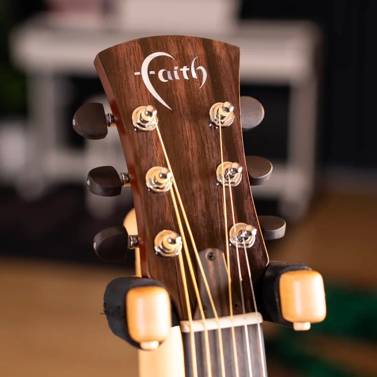 Close-up of a wooden guitar headstock with six tuning pegs and strings, logo visible near the top. ขายราคาพิเศษ