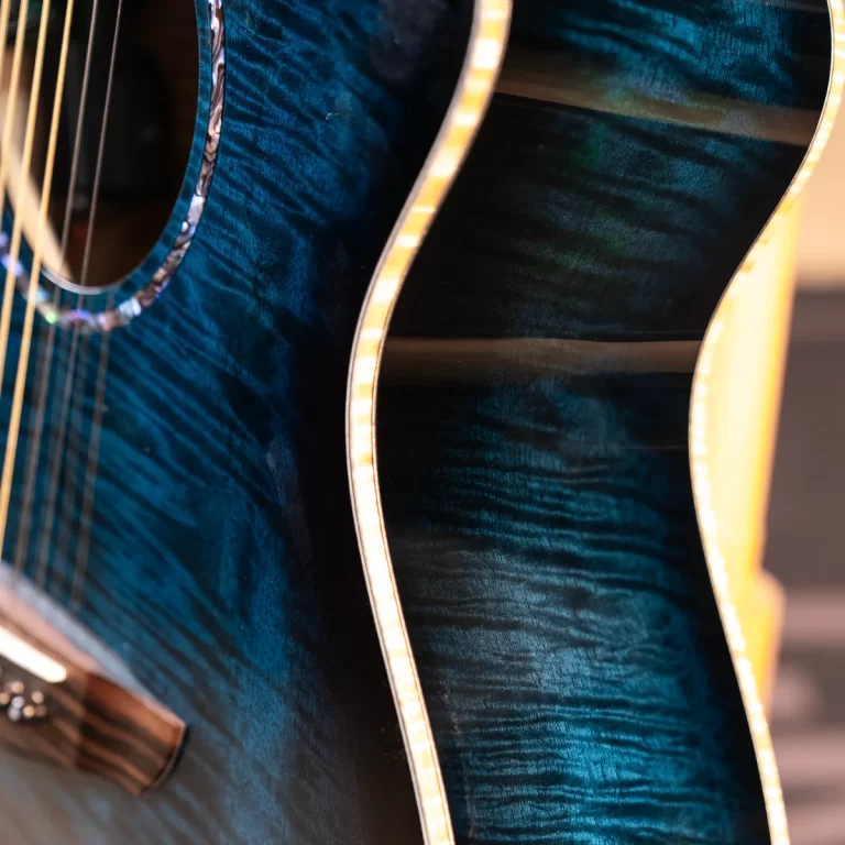 Close-up of a blue quilted wood acoustic guitar body with light binding along the edge. (informative) ขายราคาพิเศษ