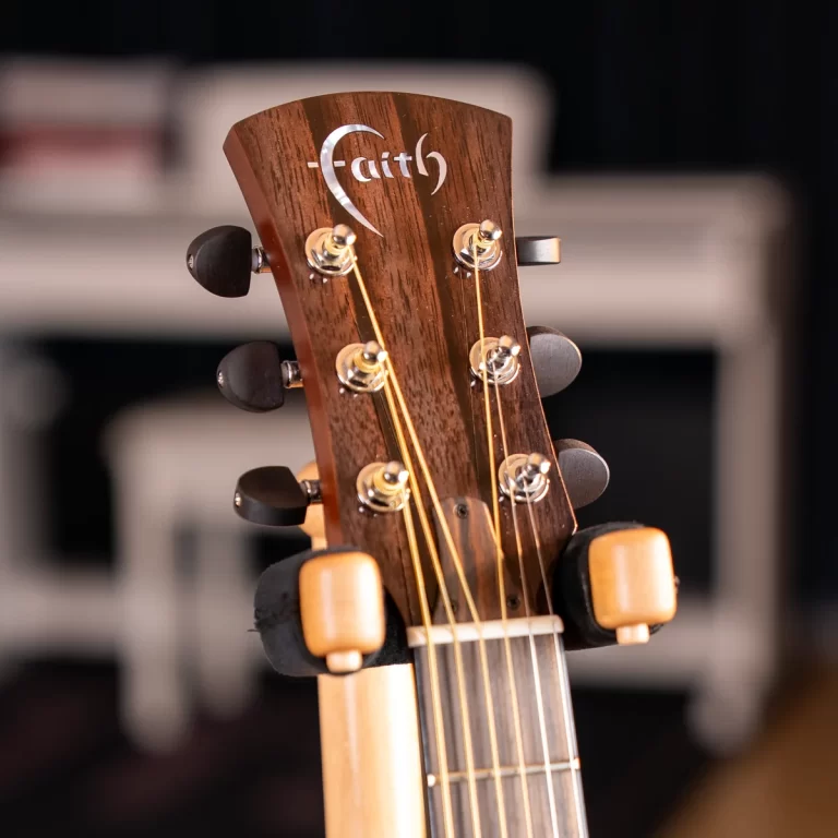 Close-up of a Faith guitar headstock with six tuning pegs and warm wood grain, strings visible. ขายราคาพิเศษ