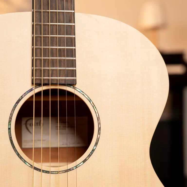 Close-up of an acoustic guitar showing the soundhole, rosette, and six strings over a light wood body. ขายราคาพิเศษ