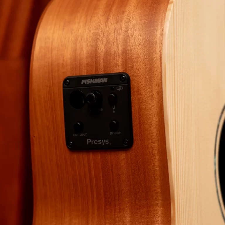 Close-up of a wooden acoustic guitar body showing a black Fishman Presys preamp plate embedded in the side panel. ขายราคาพิเศษ
