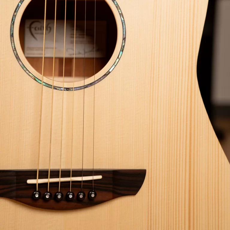 Close-up of a light wood acoustic guitar showing strings over the bridge and soundhole with a decorative rosette nearby if visible? ขายราคาพิเศษ