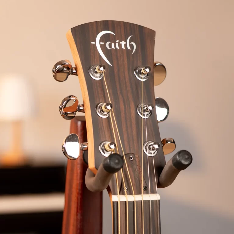 Close-up of a wooden guitar headstock with six tuning pegs and strings, featuring a white Faith logo. ขายราคาพิเศษ
