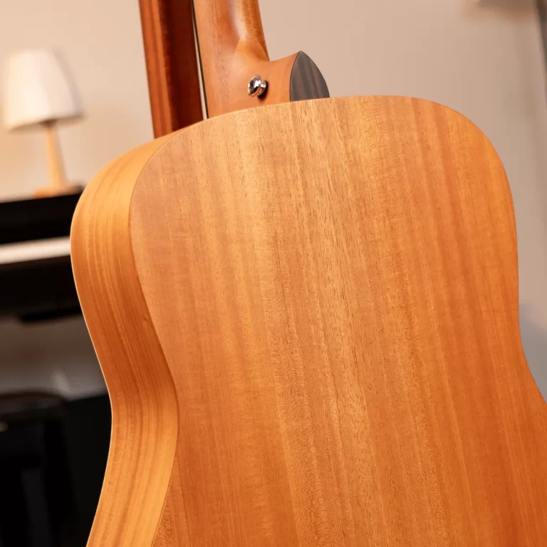 Close-up of the back of a light wood acoustic guitar, highlighting the smooth grain and curved body joint. ขายราคาพิเศษ